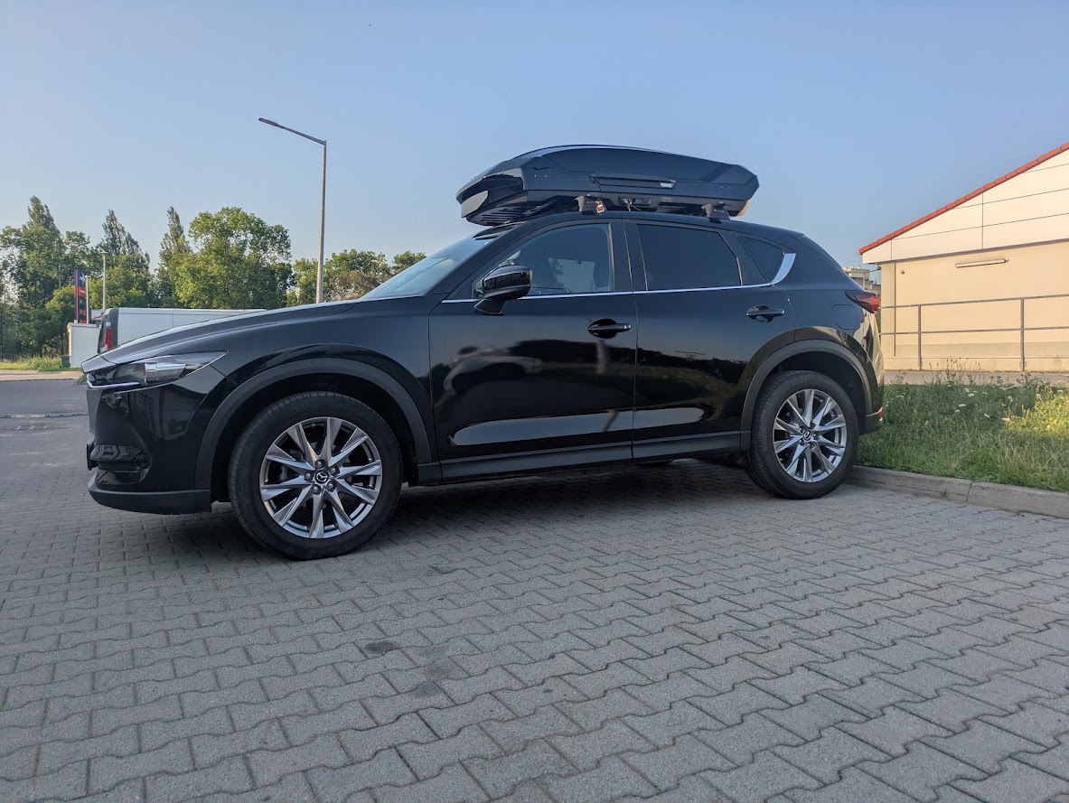 Mazda CX-5 z boxem i belkami Yakima ? przedni lewy narożnik z niskiej perspektywy